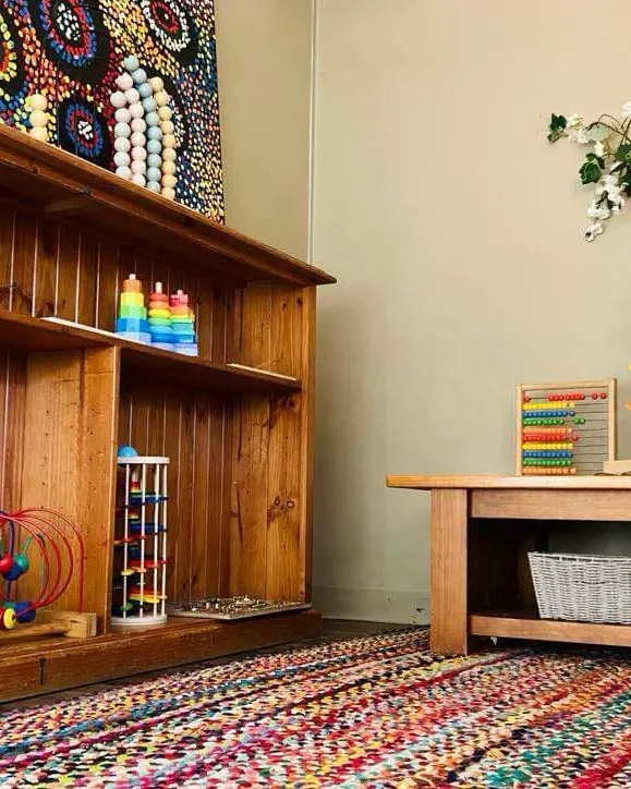Junior Kindy shelves with stacking toys and a rainbow rug