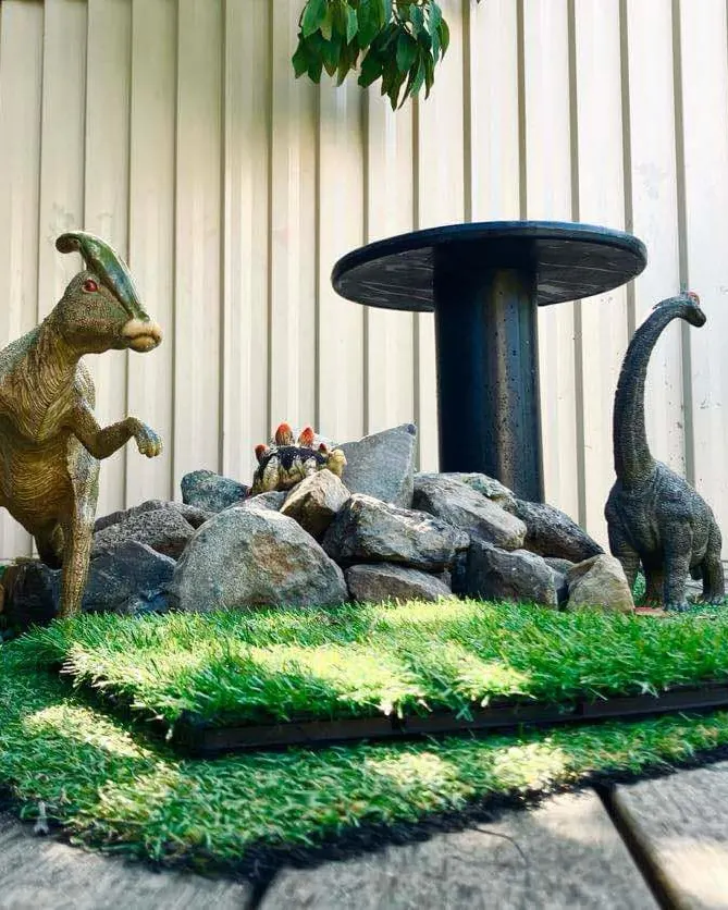 Toy dinosaurs on rocks and grass in the Junior Kindy dino space