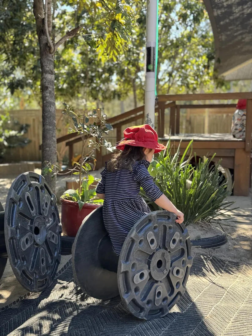 A child climbing between giant cable spools